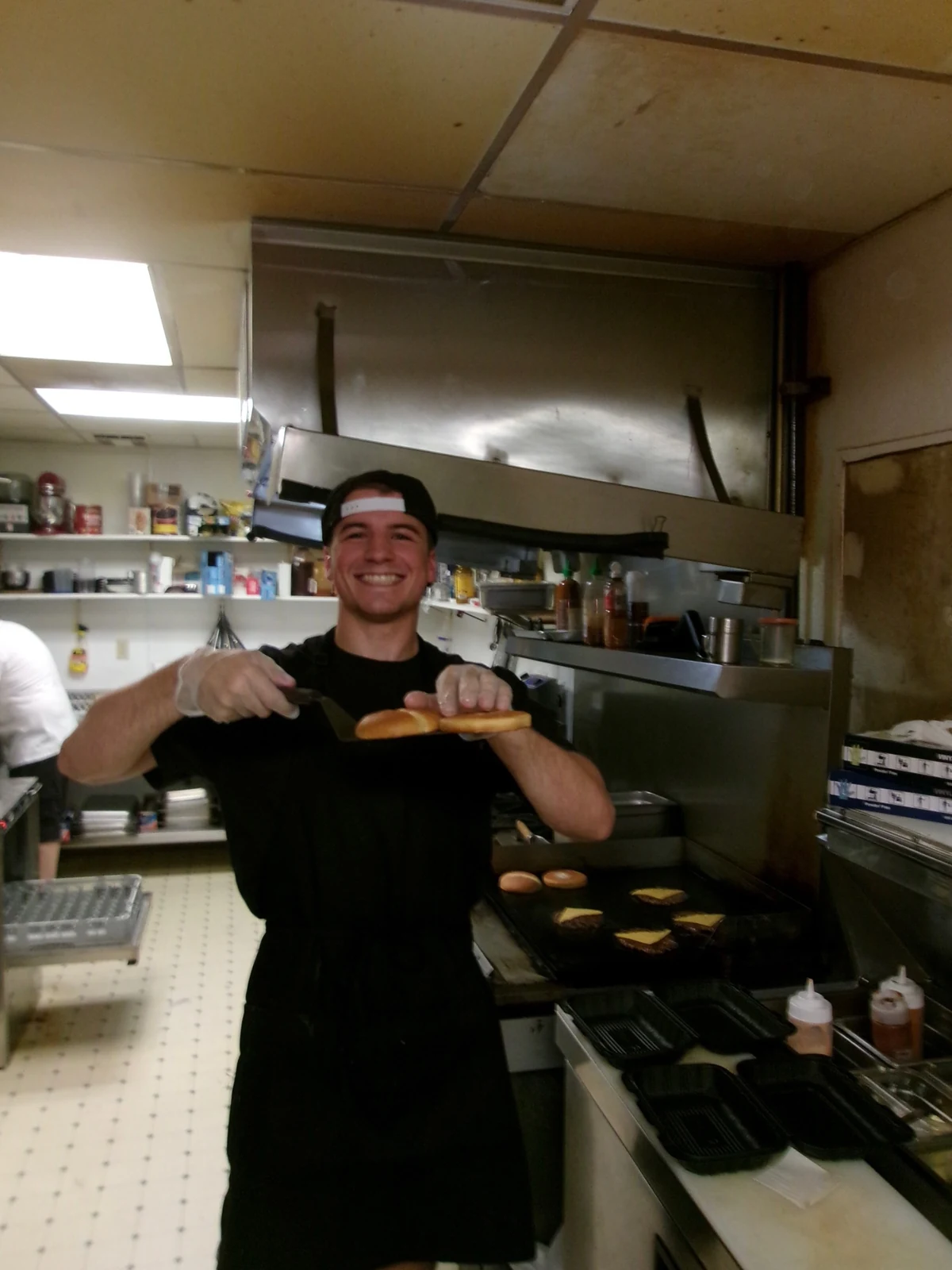 A smiling person holding plated food in the Rewsters kitchen